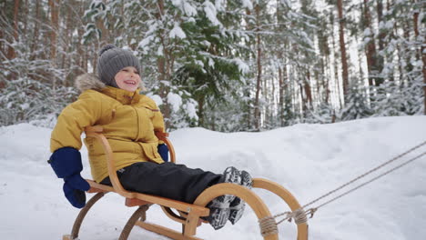 Un-Niño-Lindo-Está-Montando-Trineo-En-Un-Bosque-Invernal-Divirtiéndose-Y-Disfrutando-Durante-Un-Paseo-Familiar-En-La-Naturaleza.